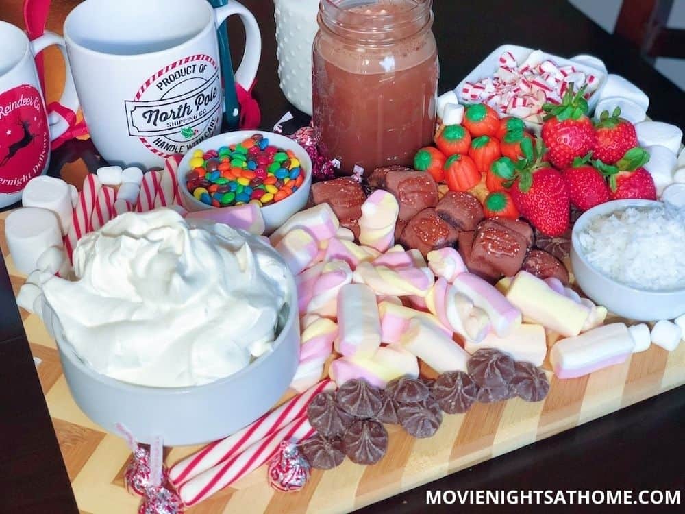 Elf Inspired Hot Chocolate Charcuterie Board with marshmallows, candy, candy corn, candy canes, coconut, and strawberries