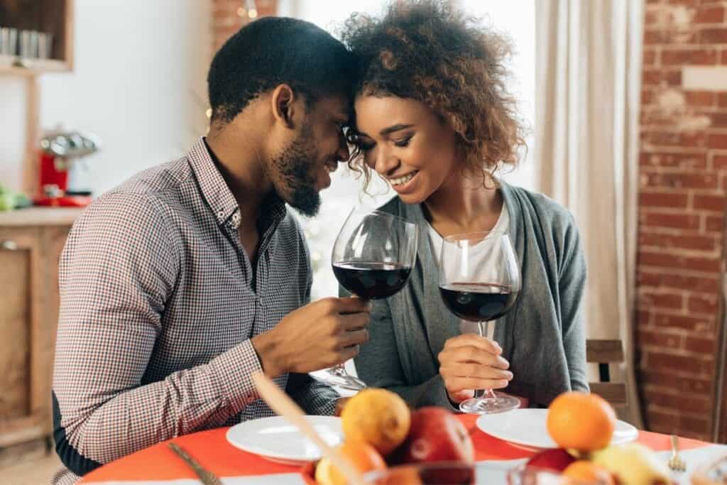 couple enjoying a romantic dinner with a glass of wine together