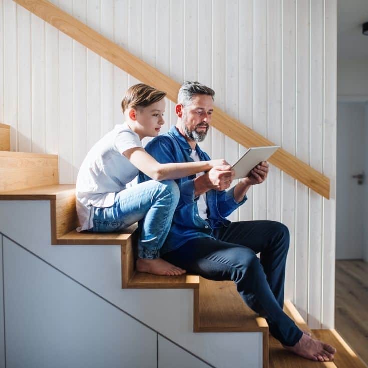 father and son on the stairs looking at an ipad