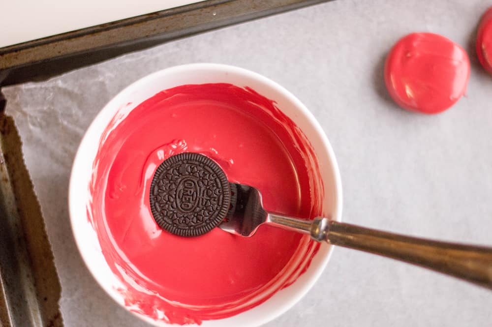 dipping the oreo into the melted candy melts