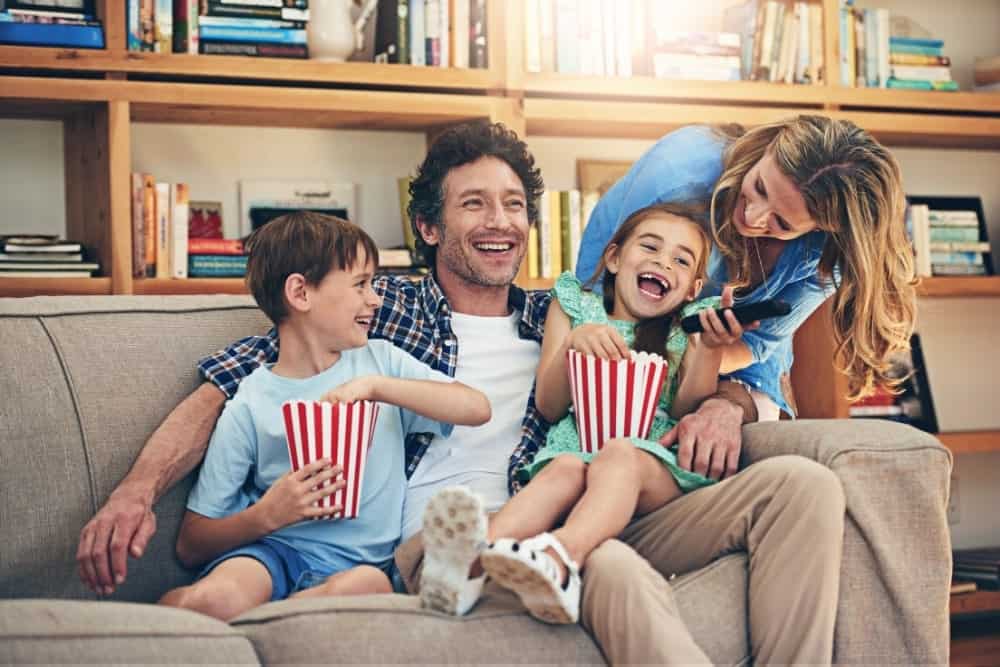 family of 4 about to watch a movie with buckets of popcorn at home