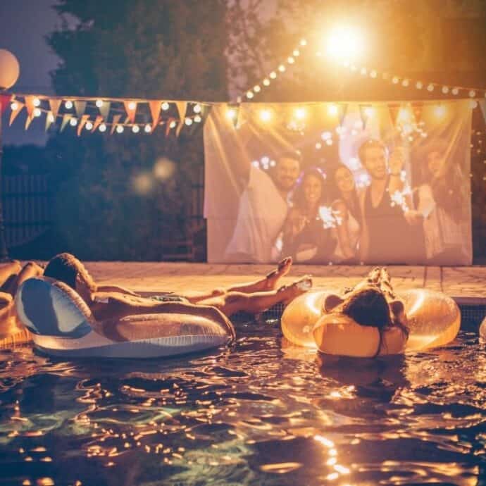 friends sitting in the pool on floats watching a movie