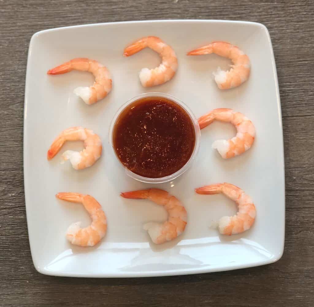 9 shrimp on a plate with cocktail sauce