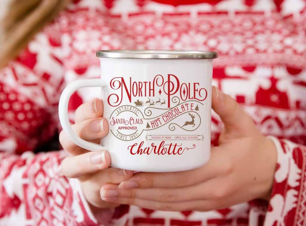 someone holding a red and white polar express party favor cocoa mug