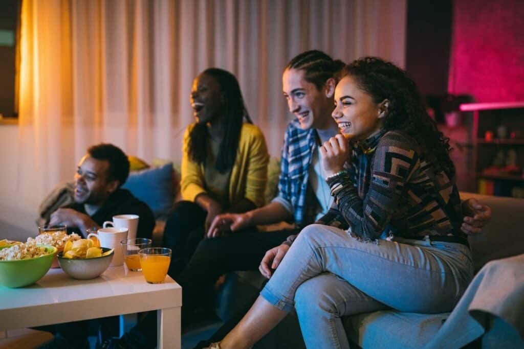 4 teenagers watching a movie on a couch