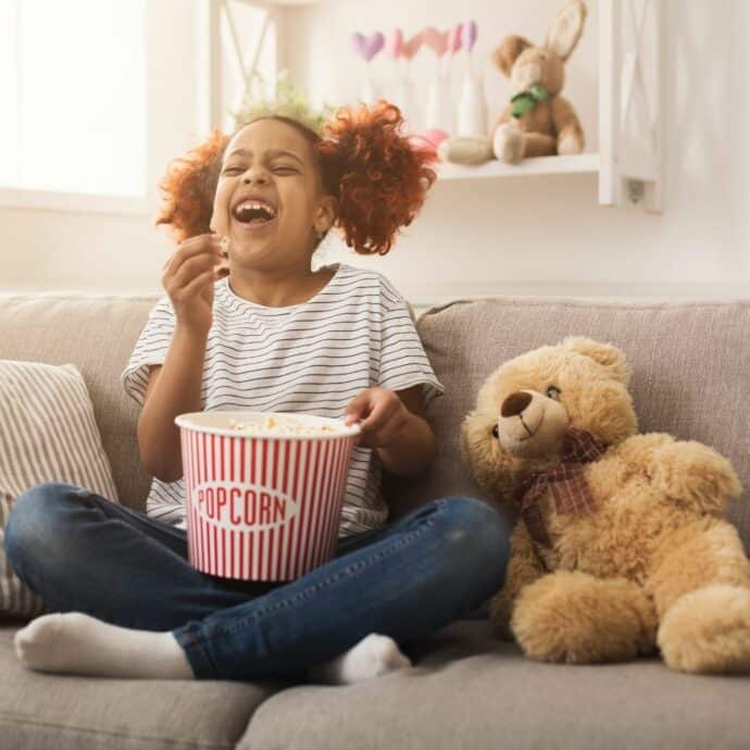 kid watching a movie eating popcorn