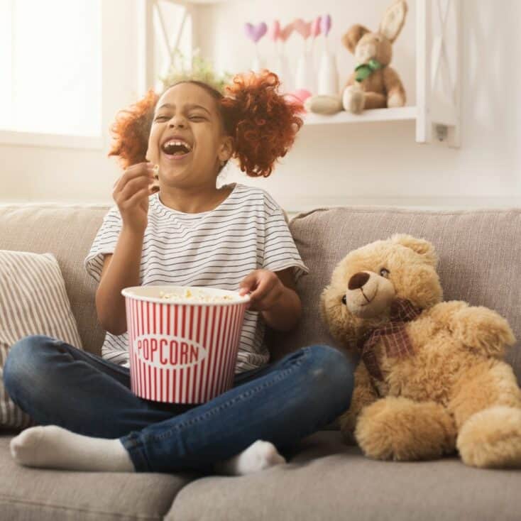 kid watching a movie eating popcorn