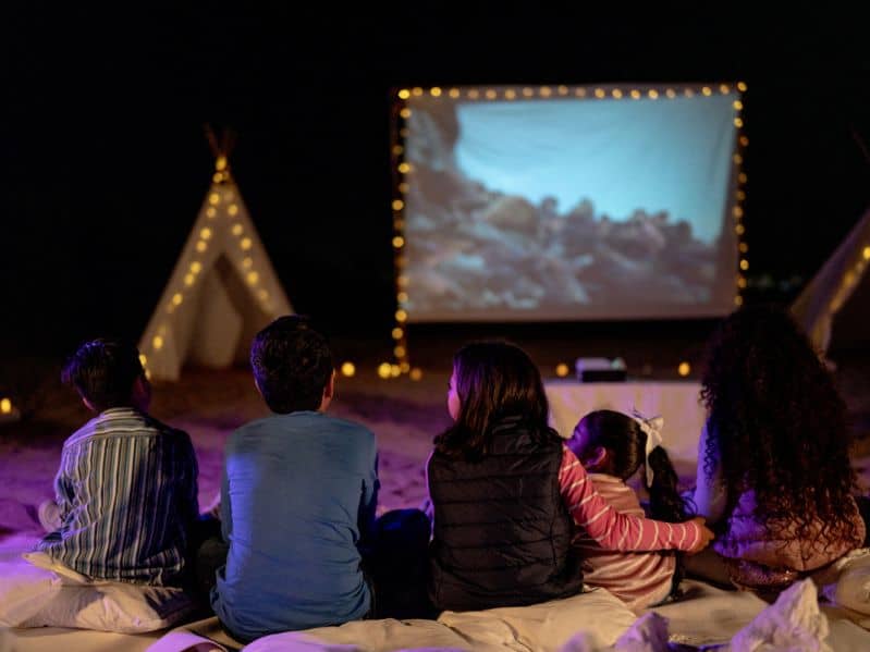 kids outside watching a movie on a projector