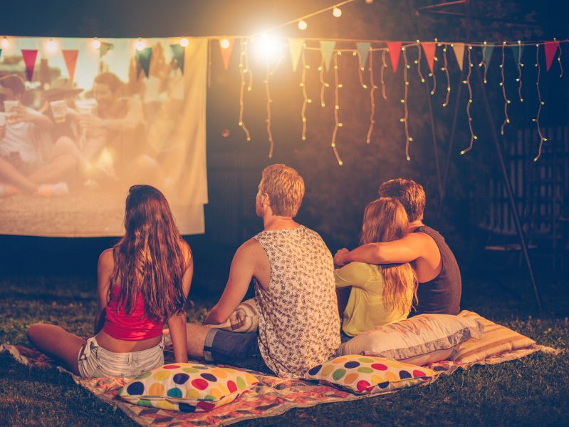 4 friends outside watching a movie on a projector screen