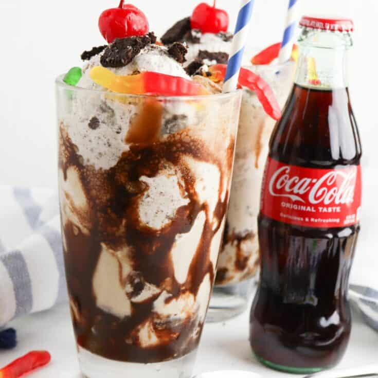 1 ice cream float with gummy worms on top with a bottle of Coke beside it