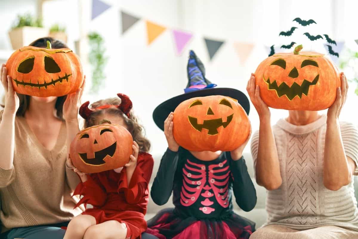 family of 4 holding jack-o-lanterns in from of their faces