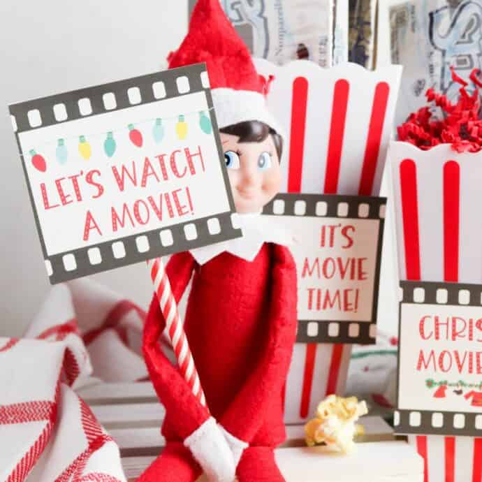 elf on the shelf holding a movie printable with a straw base