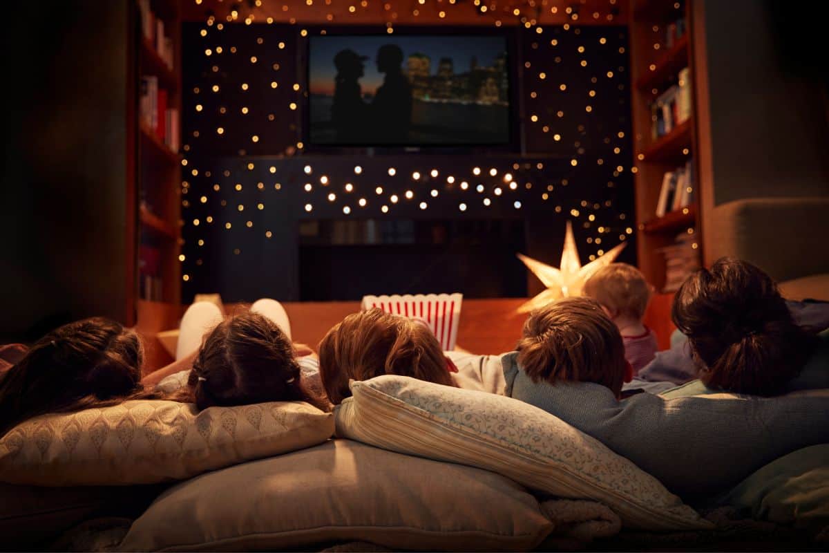 large family watching a movie indoors with the lights off