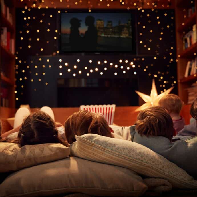indoor movie night feature image - family laying on pillows watching a movie inside