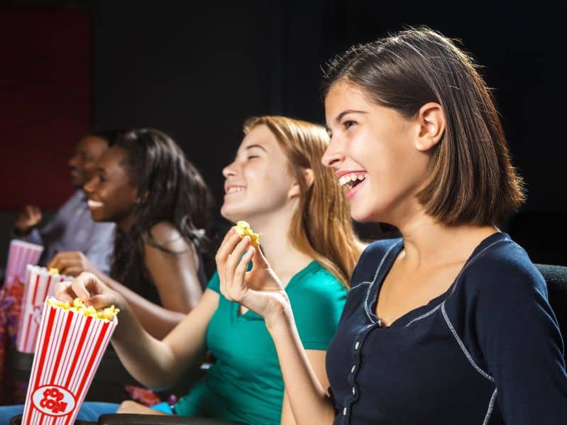 tweens eating popcorn at the movies