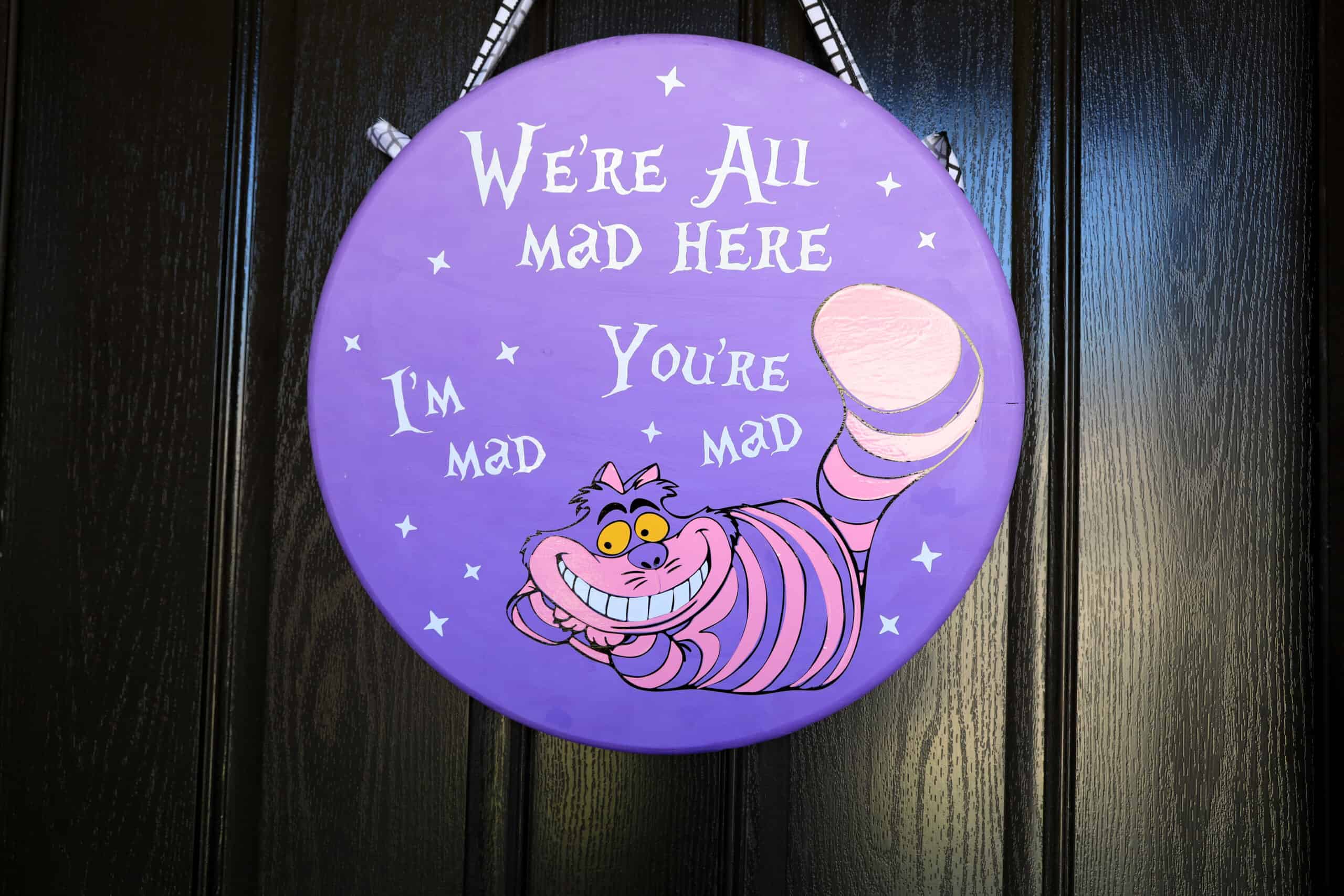 diy Cheshire Cat Wreath hung on a black door with ribbon
