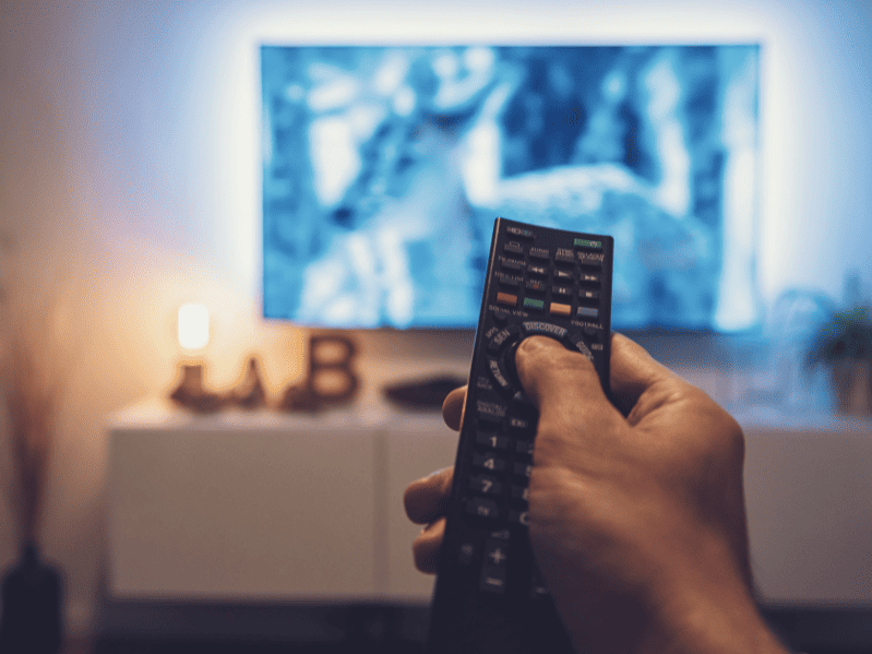 a hand holding a remote pointing it at the tv