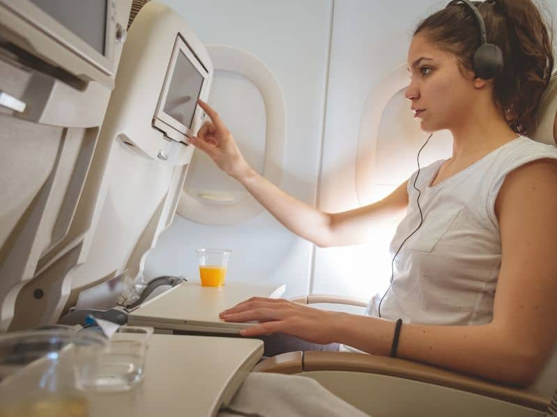 woman on a plane looking at in flight entertainment