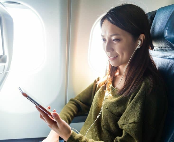 woman on a plane watching a tablet with headphones in