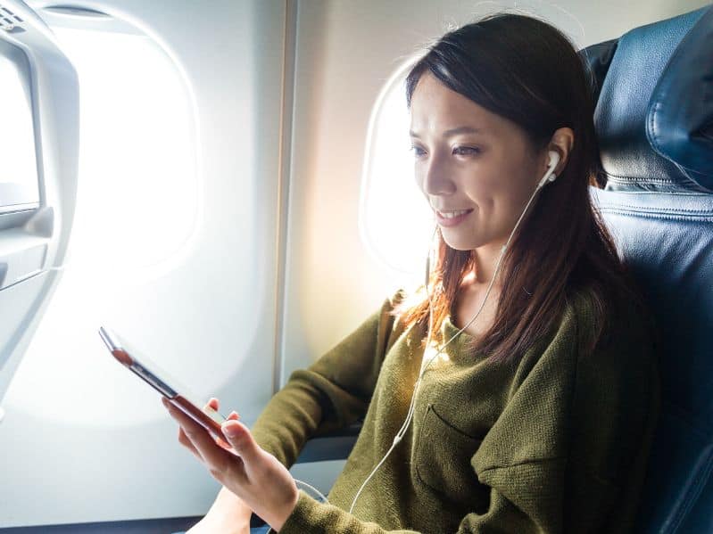 woman on a plane watching a tablet with headphones in